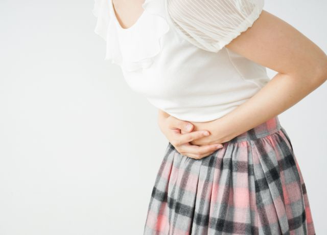 お腹に手をあて、前傾姿勢になっている女性